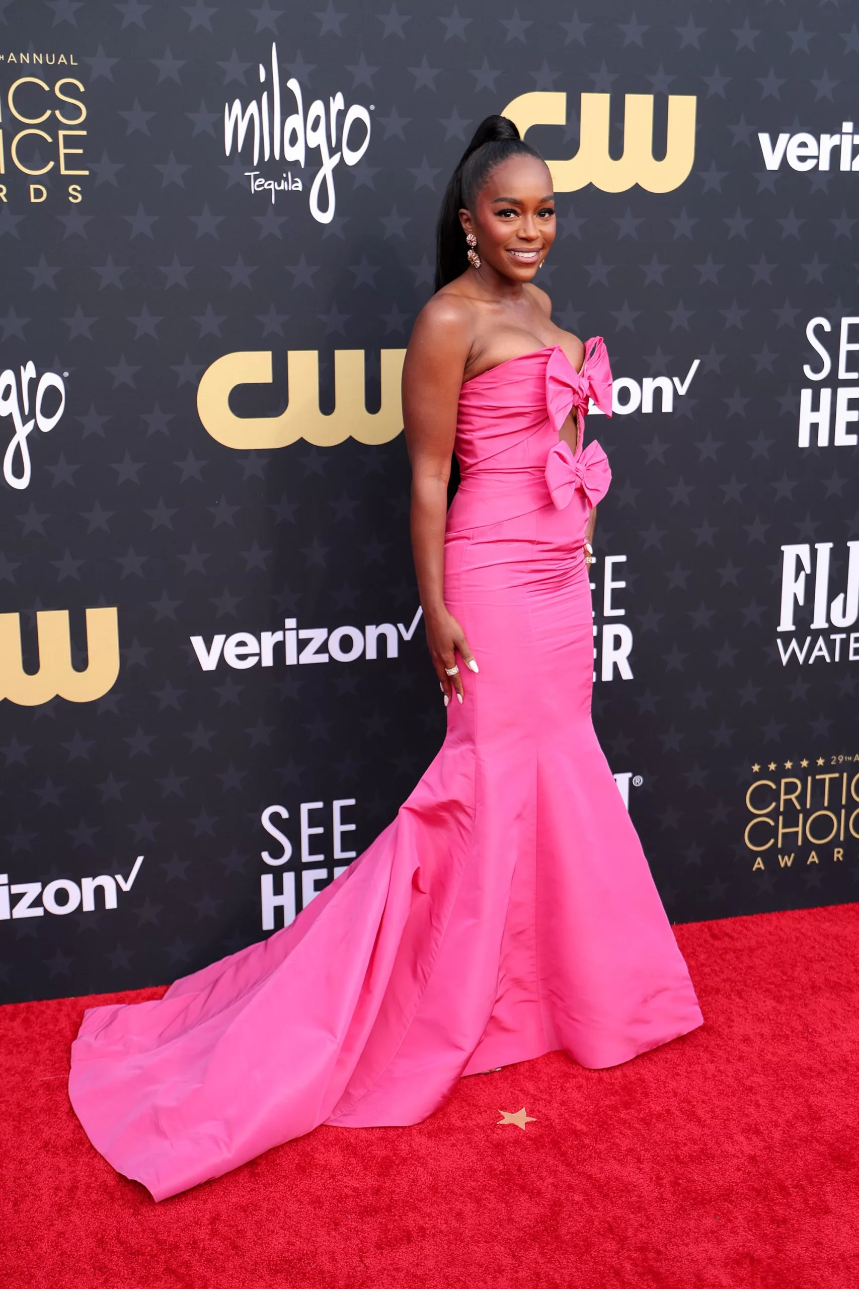 “Lessons in Chemistry” actress Aja Naomi King in a bright pink Oscar de la Renta mermaid gown with oversized pink bow accents and cut-out bodice.